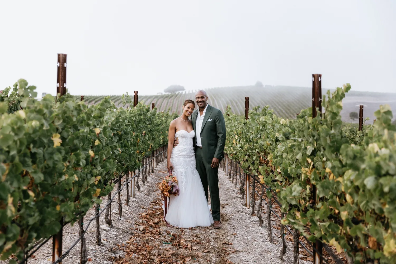 A couple standing between the vine rows at Albatross Ridge