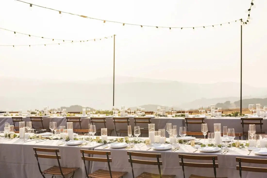 Long tables under string lights, the hazy range beyond