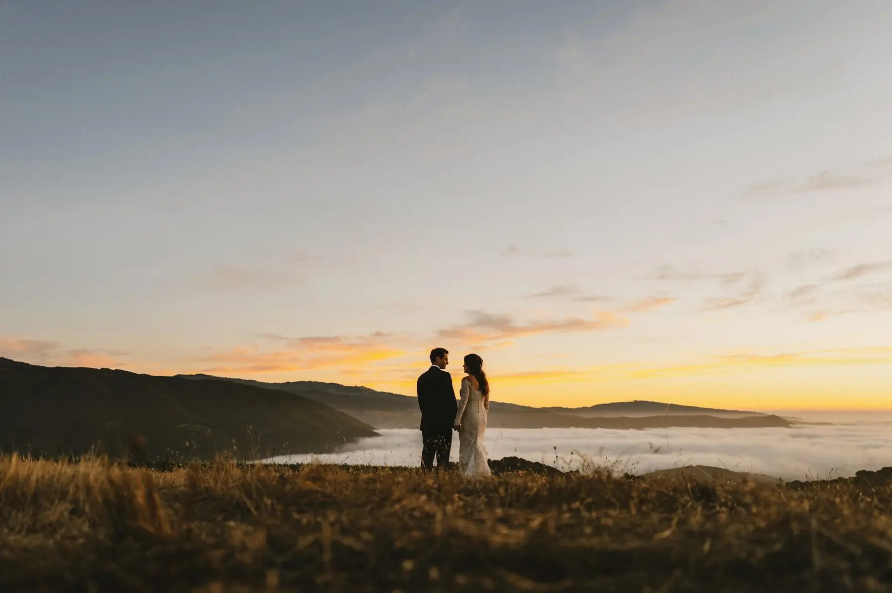A couple at sunset on the ridge, fog filling the valley below